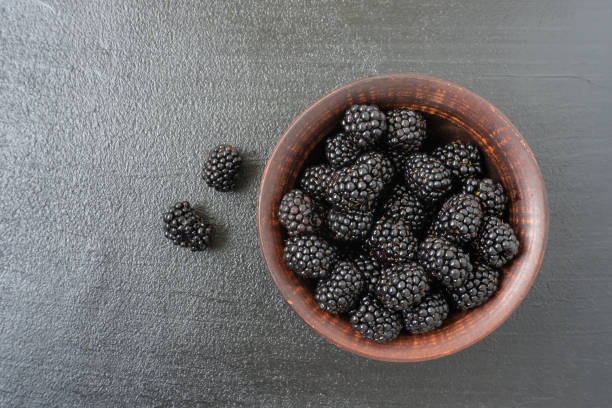 Fresh blackberries in a bowl on a dark background
