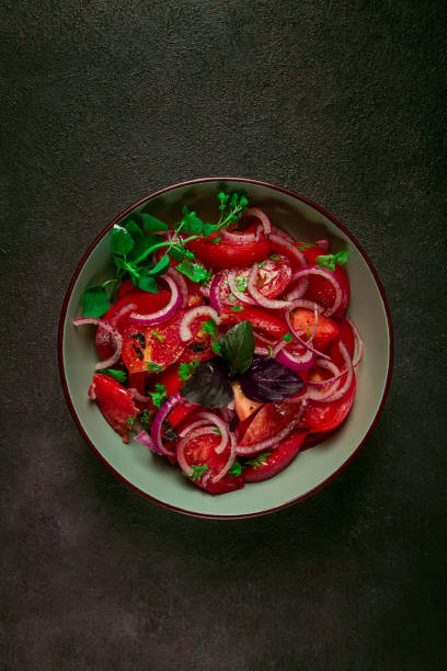 fresh tomato salad, with red onion, spices and herbs, top view, close-up, homemade,