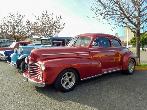 Buenos Aires, Argentina – June 05, 2023: Old red shiny 1940s Chevrolet Fleetmaster coupe street rod in a parking lot. Classic car show