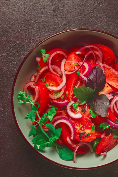 fresh tomato salad, with red onion, spices and herbs, top view, close-up, homemade,