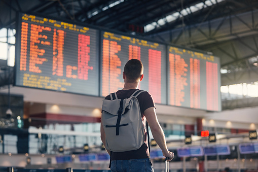 Hombre caminando con mochila y maleta caminando por la terminal del aeropuerto photo