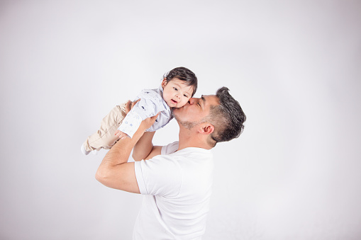 Beautiful photo of Dad holding his baby on light photo studio background. Family and baby concept.