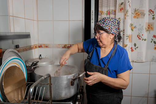 Close up of unrecognizable latin woman cooking onion and meat in a pot, for filling chilean baked empanadas