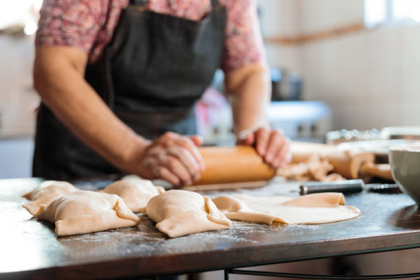 istock Unrecognizable Latin Woman Kneading Dough with a Rolling Pin, for making Empanadas in her Countryside Home Kitchen 1548763055
