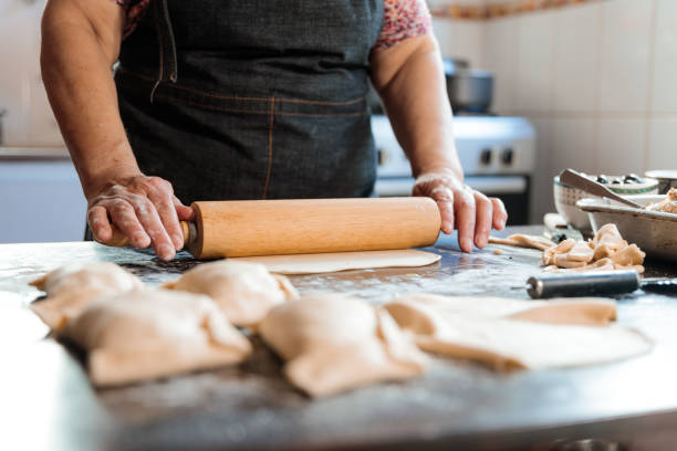 istock Unrecognizable Latin Woman Kneading Dough with a Rolling Pin, for making Empanadas in her Countryside Home Kitchen 1548763359