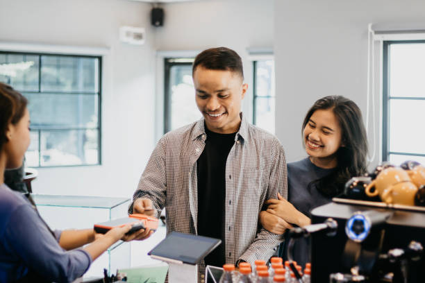 istock Beautiful Couple Paying at Cashier Using Contactless Card 1548768131