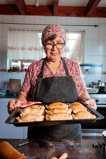 Flavors of Heritage: Latin Elderly Woman Preparing Chilean Baked Beef Empanadas in the Warmth of Her Home Kitchen