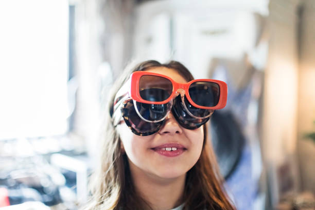 Child having fun in clothing store and trying on sunglasses
