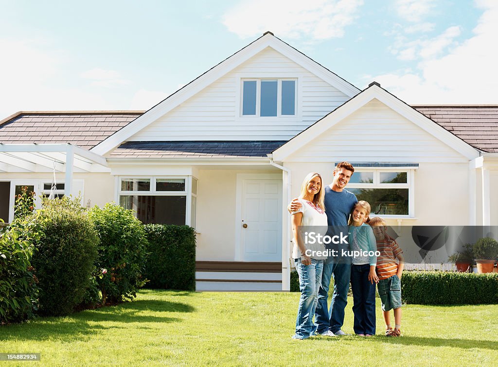 Famiglia caucasica in piedi davanti a una casa di lusso - Foto stock royalty-free di Casa