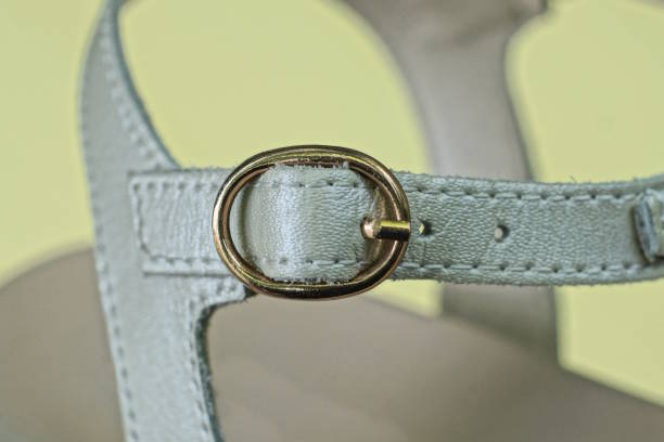 one closed metal clasp on a white leather sandal harness