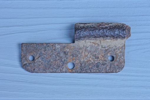 one old rusty brown door hinge lies on a gray table