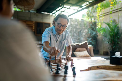 Senior man getting excited while playing chess with his friend. Senior Retirement Friends Happiness