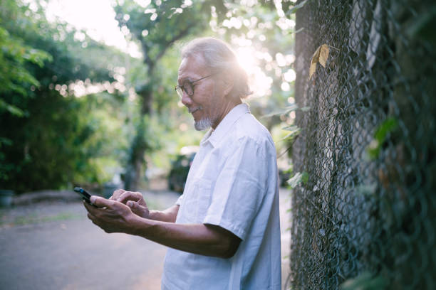 istock Happy asian senior man using mobile phone outdoor. 1548853231