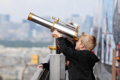 A boy is looking through telescope