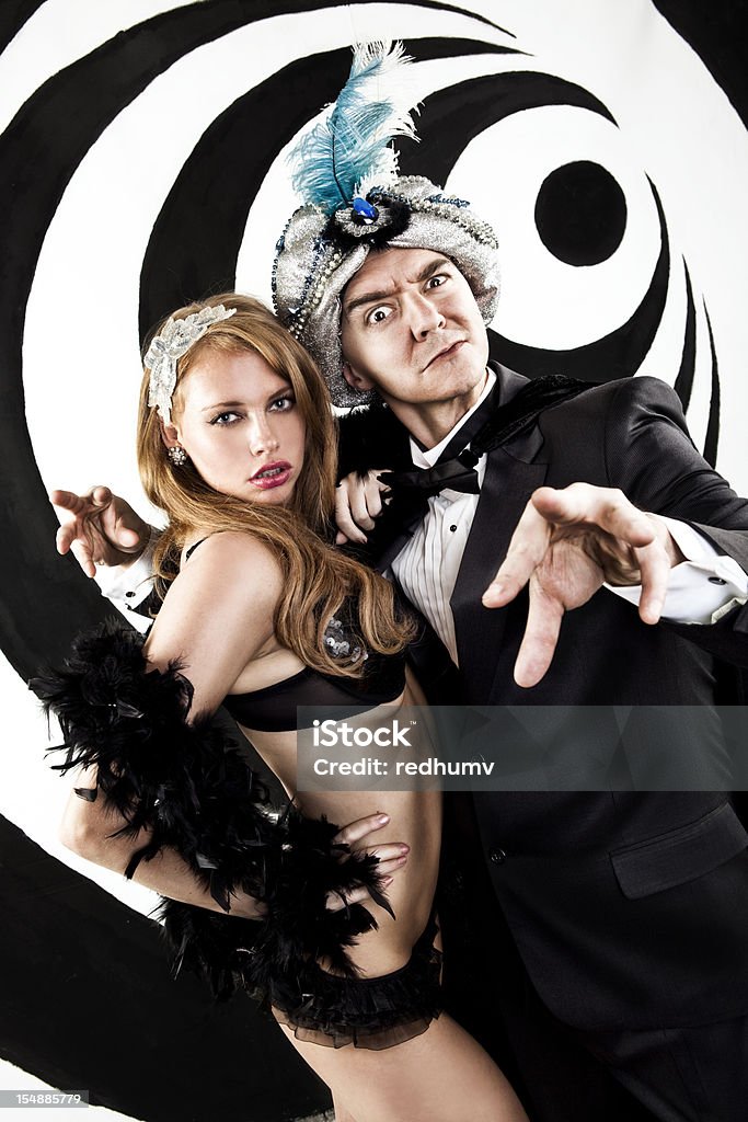 Retro Hypnotist and Beautiful Assistant A stock photo of a Hypnotist inducing a trance standing next to his beautiful young female assistant on a black and white swirl background. Magician Stock Photo