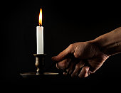 Hand holding a lit candle in the dark