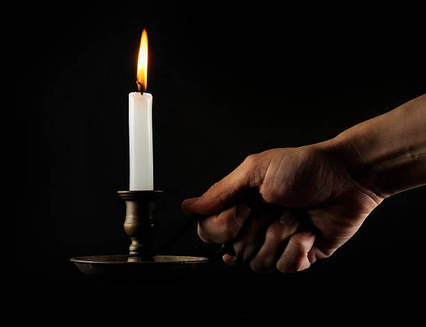 Hand holding a lit candle in the dark stock photo