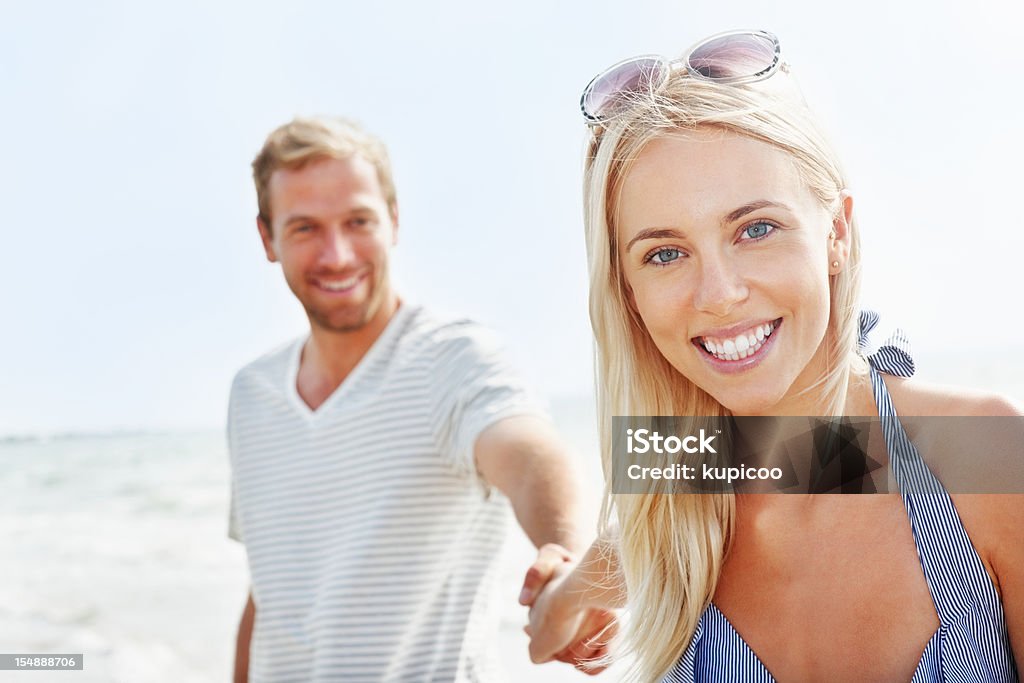 Hermosa joven mujer sosteniendo la mano de novio en la playa - Foto de stock de Cerca de libre de derechos