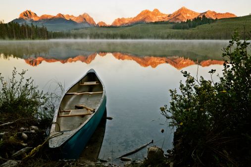 Beautiful first light hitting Sawtooth mountain range as seen from Little Redfish Lake, Stanley, Idaho, USA with a kayak ready to go
