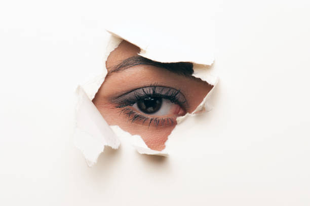 istock looking through a hole in the paper 154888810