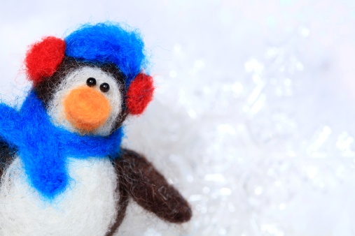 XXXL photo - macro of a small felt penguin made entirely from scratch by the photographer from loose wool and styrofoam.  Short depth of field so the background is sparkly defocused snow.