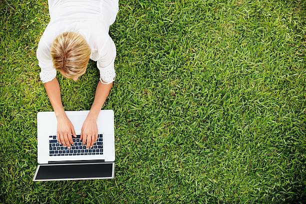 istock Top view of young girl lying on grass and working 154890255