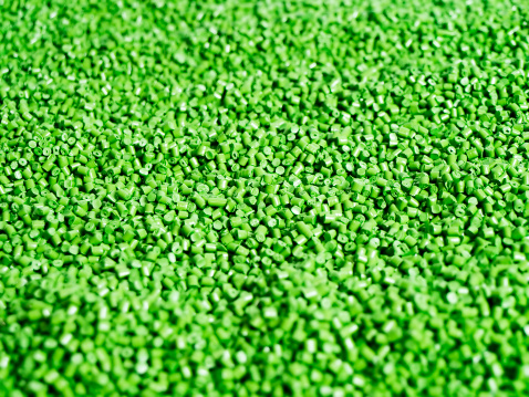 Close-up flat lay of light green plastic resin (Masterbatch) polymer granules on a  tray