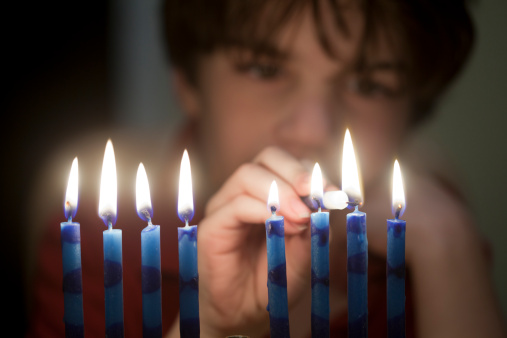 Boy, age 8, lights the candles of the Hanukkah Menorah.