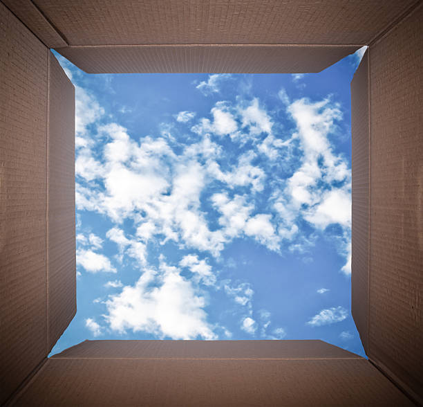 Camera Perspective inside cardboard box looking at blue sky stock photo