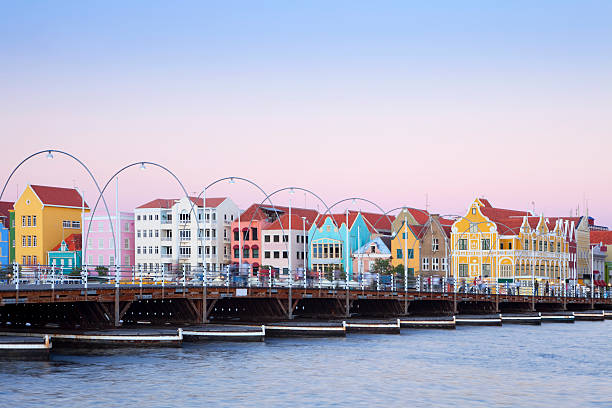 Colorful houses of Willemstad, Curacao with bridge The coloured houses of Willemstad, Curaçao in the Netherlands Antilles. The famous Queen Emma pontoon bridge in the foreground. Photographed just after sunset. curaçao stock pictures, royalty-free photos & images