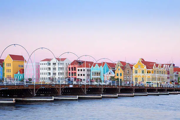 The coloured houses of Willemstad, Curaçao in the Netherlands Antilles. The famous Queen Emma pontoon bridge in the foreground. Photographed just after sunset.