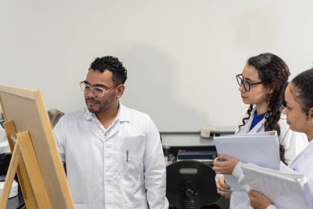 istock Latino researcher on a board explaining to his female lab partners 1548913352