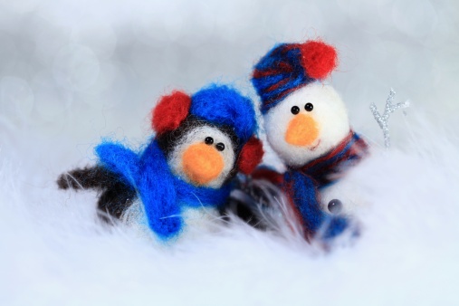 XXXL photo of a penguin and a snowman with selective focus on their eyes and short depth of field for a soft snowy portrait effect with the background sparkles and foreground feathers blurred.  Both characters were made entirely from scratch by the photographer.