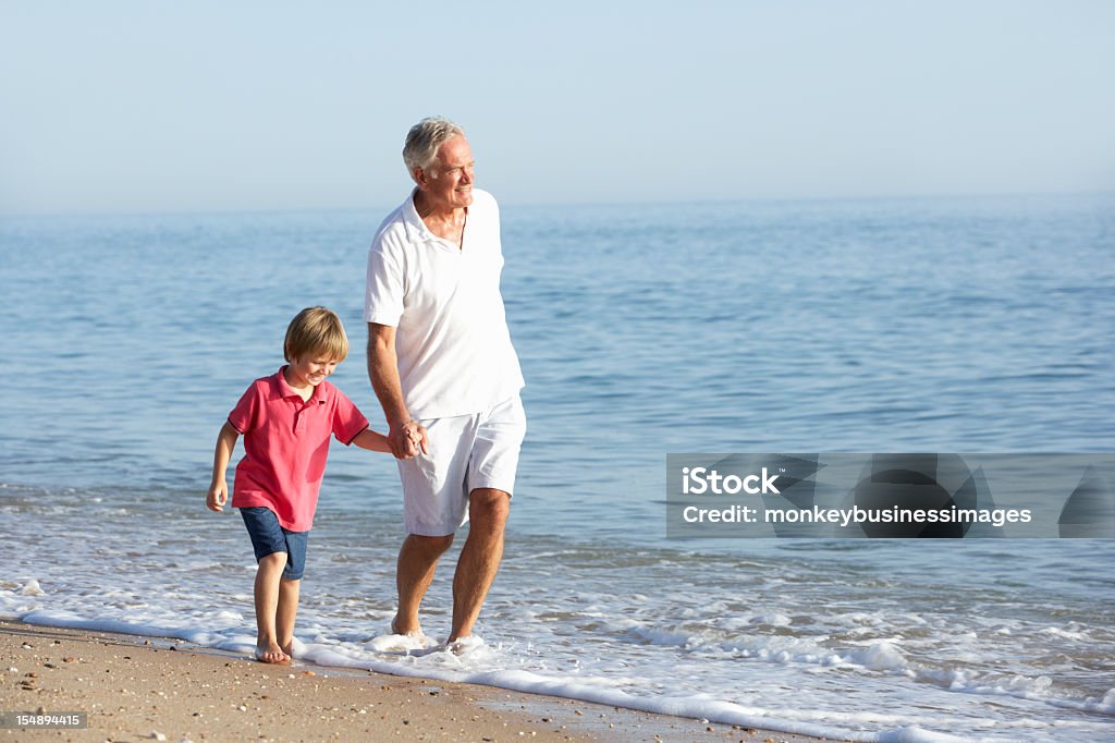 Großvater und Enkel, die zu Fuß am Strand - Lizenzfrei Familie mit mehreren Generationen Stock-Foto