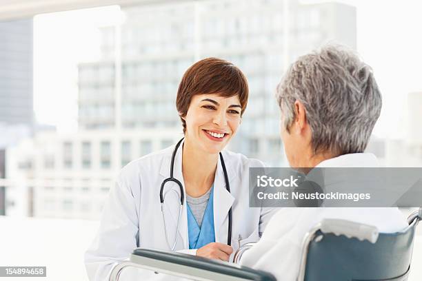 Medico Controllando Sul Suo Paziente - Fotografie stock e altre immagini di 60-69 anni - 60-69 anni, Accovacciarsi, Accudire