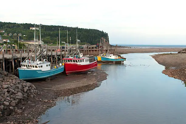Fishing boats at low tide at the wharf in Alma, Bay of Fundy, New Brunswick, Canada. Home of the largest tides in the world.