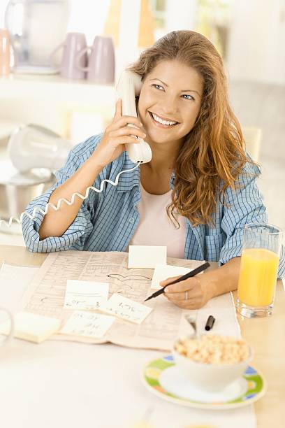 Young woman writing notes in kitchen stock photo