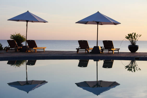 istock two pairs of sunchairs with reflection in pool 154894878