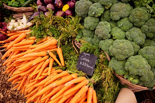 A vibrant display of fresh carrots and broccoli arranged together in a market stall  at the Oranjezicht Food Market in Cape Town South Africa