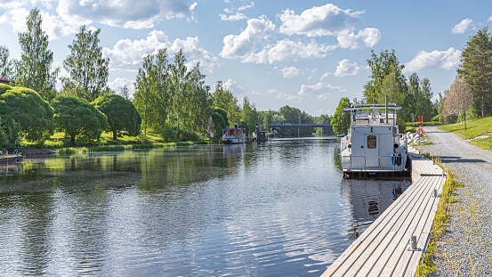 Jämsänjoki river on a sunny summer day with blue sky, whote clouds and anchored boats.