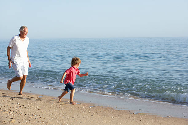 istock Grandfather And Grandson Running Along Beach 154904301