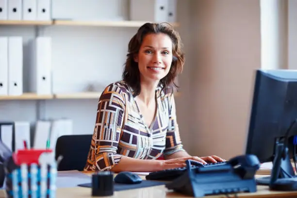 Photo of Smiling businesswoman at office desk with a computer