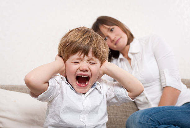 Crying boy is covering his ears stock photo
