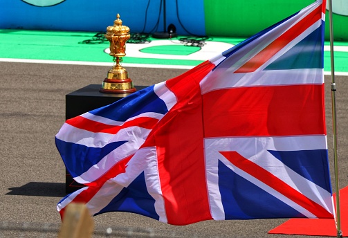 The official Royal Automobile Club trophy for the British Grand Prix on a plinth at the head of the starting grid at Silverstone. Set with billowing British Union Jack flag.