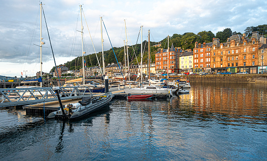 Rothesay, Scotland, UK - 13th July 2023: Part of the marina of Rothesay, Isle of Bute, with yachts and other leisure craft, moored. Also the houses and shops on part of the mainly 19th Century Esplanade.