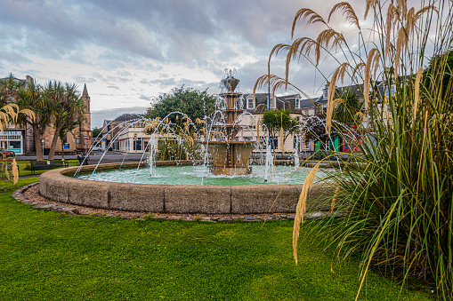 Rothesay, Scotland, UK - 13th July 2023: The fountain on the Esplanade in Rothesay, Isle of Bute, outside the Winter Gardens (not shown). It is surrounded by pampas grass and palm trees, indicative of Rothesay's mild climate situated in a sheltered area and moderated by the Gulf Stream.