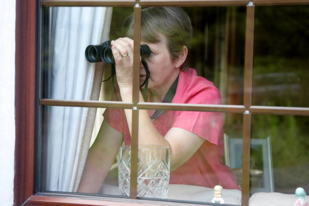 nosey vizinho na janela com binóculos - nosy - fotografias e filmes do acervo