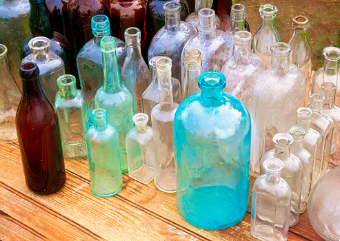 A collection of antique bottles of various sizes, shapes and colors displayed at a Cape Cod flea market.