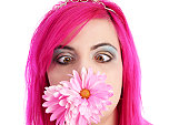 Crosseyed pink-haired girl with flowers in mouth.