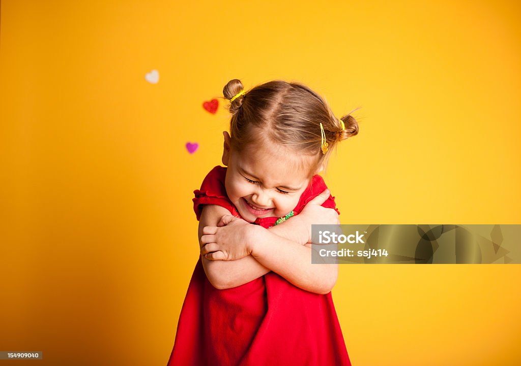 Great Big Valentine Hug, Cute Girl Hugging Herself Color image of a little girl giving herself a big Valentine hug with hearts in the background on yellow.  Child Stock Photo